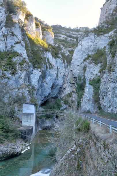 a paved road going into the veral river canyon, with high grey rock gorge at sunset in foz de binies rural area, in aragon, spain - conutryside imagens e fotografias de stock