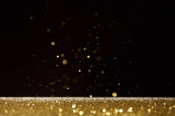 istock selective focus of bright golden sparkles on table isolated on black 1098358798