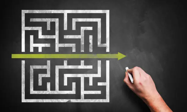 Photo of hand drawing a shortcut to a maze on a chalkboard