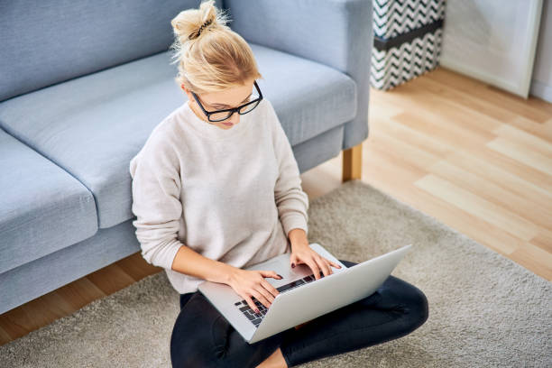 istock Woman sitting on floor in apartment and using laptop 1098364634