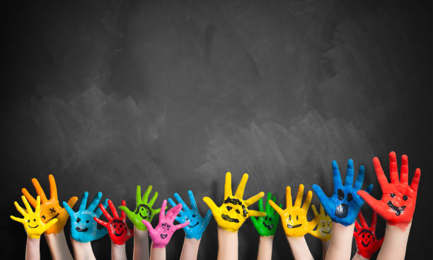 painted hands in front of a blackboard stock photo