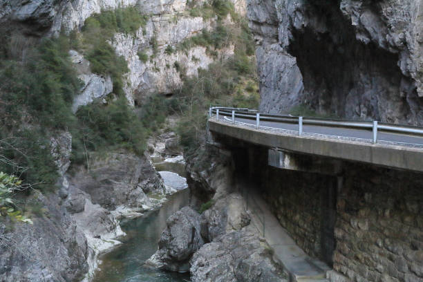 eine asphaltierte straße, die in der g-river-canyon, mit hohen grauen felsschlucht bei sonnenuntergang in foz de binies ländlichen gegend, in aragon, spanien - conutryside stock-fotos und bilder