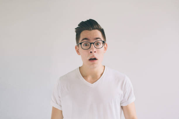 istock Omg No way Very shocked young man with glasses is looking at the camera. Student nerd is wearing in a white t-shirt, standing isolated on a white background 1098366426