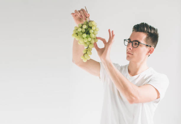 istock man holding grape, close up. concept. isolated on white. Nerd is wearing glasses. 1098366682