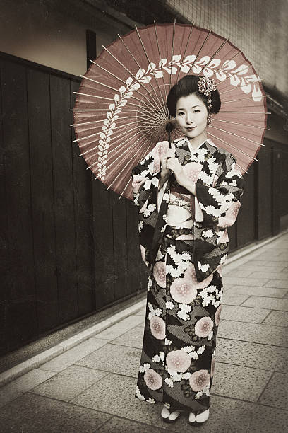 Vintage Japanese Kimono A stock photo of a beautiful young girl dressed in traditional Japanese Kimono dress and parasol while standing on a quiet street in Kyoto, Japan. kimono photos stock pictures, royalty-free photos & images