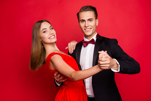 Portrait of two nice sweet lovely attractive adorable gorgeous charming cheerful positive affectionate people married spouses wife husband dancing isolated over bright vivid shine red background