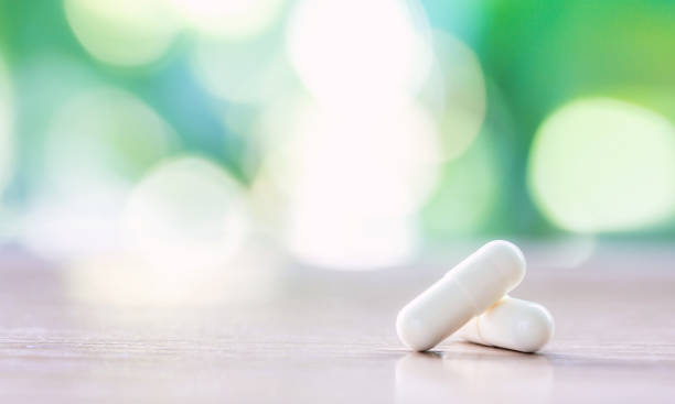 녹색 자연 배경으로 나무 테이블에 흰 약 캡슐 - capsule pill white nutritional supplement 뉴스 사진 이미지