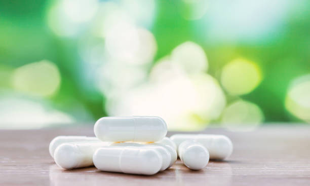 istock white medicine capsule on wooden table with green natural background 1098381908