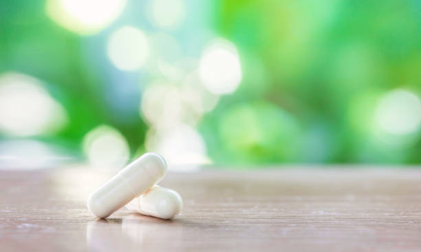 istock white medicine capsule on wooden table with green natural background 1098382000