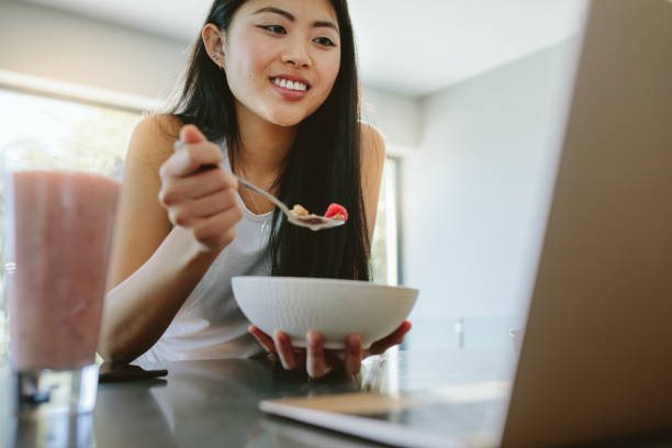 istock Woman having breakfast and using laptop 1098382138