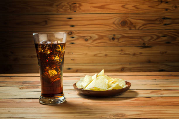 istock Potato chips with cola on a wooden background 1098384312