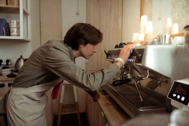 istock Dark-haired barista with nose piercing cleaning coffee equipment 1098387616