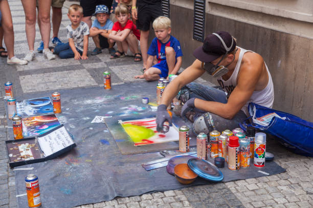 Prague, Czech Republic - July 16 2018: A street artist painting with spray colors and people watching him