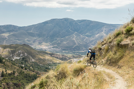 An experienced and well equipped male mountainbiker is riding on a narrow single trail into a valley on the south side of the Andalucian Sierra Nevada which is a mountain range in the province of Granada and, a little further, Málaga and Almería in Spain. It contains the highest point of continental Spain and the third highest in Europe after the Caucasus Mountains and the Alps, Mulhacén at 3,479 metres (11,414 ft) above sea level. It is a popular tourist destination. Parts of the range have been included in the Sierra Nevada National Park. The range has also been declared a biosphere reserve.
Canon EOS 5D Mark IV, 1/320, f/9, 43 mm.