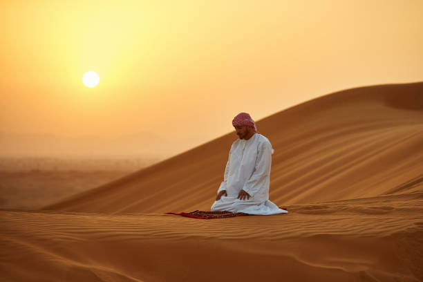 istock Arab man praying on mat in desert during sunset 1098396818