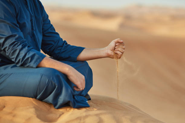 istock Low section of Arab man throwing sand in desert 1098400924