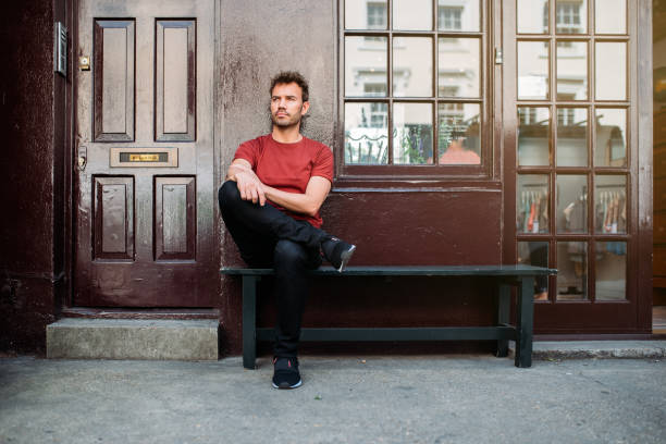 istock Man sitting in a bench on a beautiful maroon background 1098407780