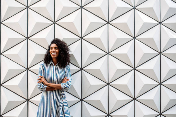 Happy pretty woman looking away smiling Happy pretty woman looking away smiling on a beautiful minimalist triangle shape wall background african american architecture stock pictures, royalty-free photos & images