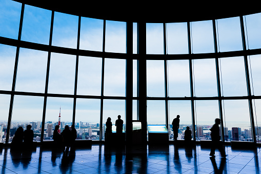 Viewing Level of Roppongi Hills Tower. Silhouettes of tourists looking out over Tokyo, Tokyo City with Toyko Tower visible through the windows.