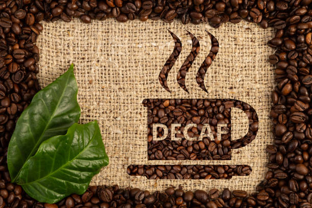 Cup with decaf text written Cup with decaf text written as aroma of no-caffeine hot beverage inside scattered coffee beans frame on brown burlap bag background decaffeinated photos stock pictures, royalty-free photos & images