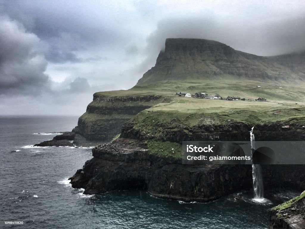 Gásadalur with Múlafossur Waterfall Gásadalur with Múlafossur Waterfall on a rainy day, Vágar, Faroe Islands. Atmospheric Mood Stock Photo
