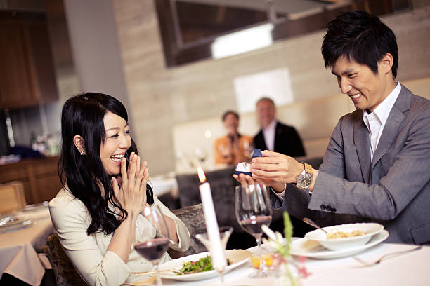 Japanese man proposing to happy Japanese woman over dinner stock photo