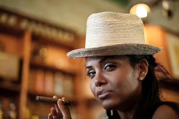 Cute latin woman in a bar with a cigar.