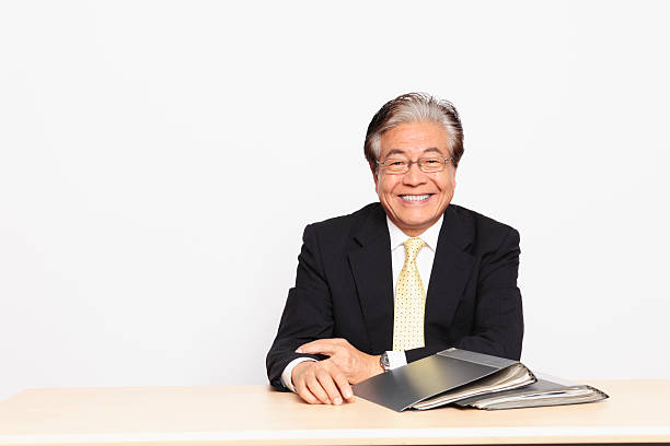 Japanese Businessman sitting at his desk, smiling stock photo