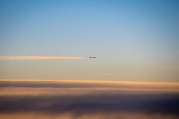 Condensation trails behind airplane in high altitude glowing in sunlight