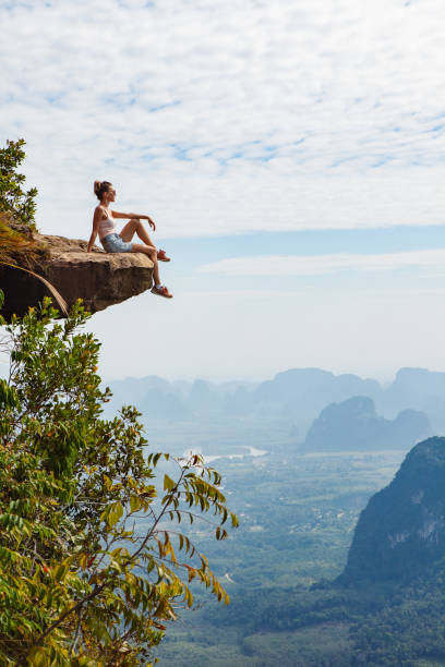 młoda dziewczyna podróżniczka siedz�ąca na klifie - vertical panorama zdjęcia i obrazy z banku zdjęć