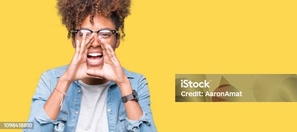 Beautiful Young African American Woman Wearing Glasses Over Isolated Background Shouting Angry Out Loud With Hands Over Mouth Stock Photo - Download Image Now