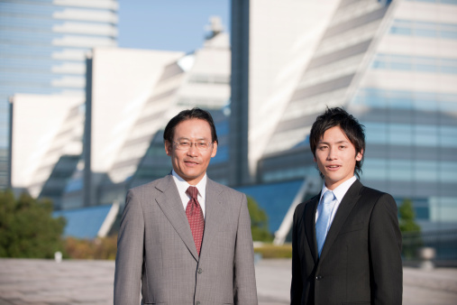 Japanese Men wearing a smart suit in front of commercial backdrop.