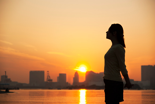 A silouette of a relaxed female at Sunset at Odaiba Beach, Tokyo, Japan.
