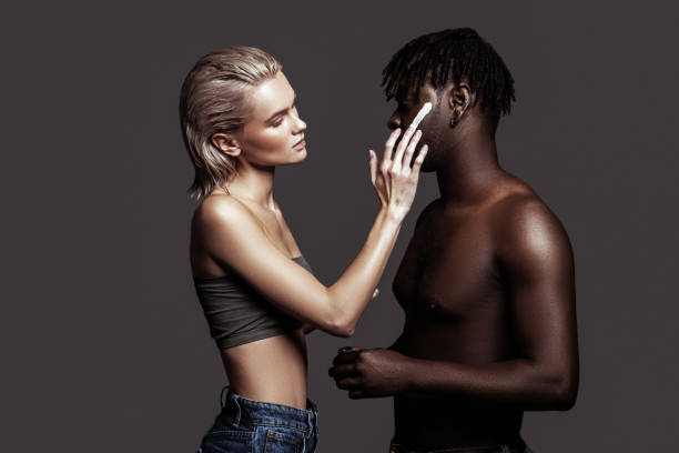 istock Blonde-haired model putting some cream on African-American man 1098431876