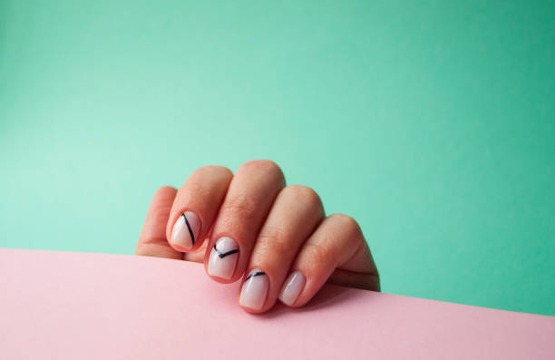 Young woman's hand with beautiful manicure on blue and pink background with copyspace.