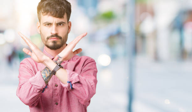 istock Young handsome man wearing pink shirt over isolated background Rejection expression crossing arms doing negative sign, angry face 1098434706