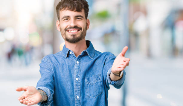 istock Young handsome man over isolated background looking at the camera smiling with open arms for hug. Cheerful expression embracing happiness. 1098436094