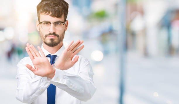 istock Young handsome business man wearing glasses over isolated background Rejection expression crossing arms and palms doing negative sign, angry face 1098436232