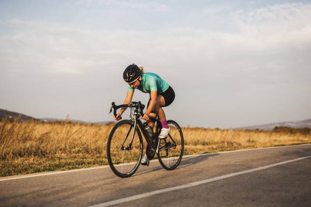 coureur cycliste féminine sur la route - vélo de course photos et images de collection