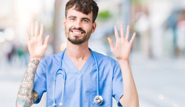 istock Young handsome nurse man wearing surgeon uniform over isolated background showing and pointing up with fingers number ten while smiling confident and happy. 1098438092