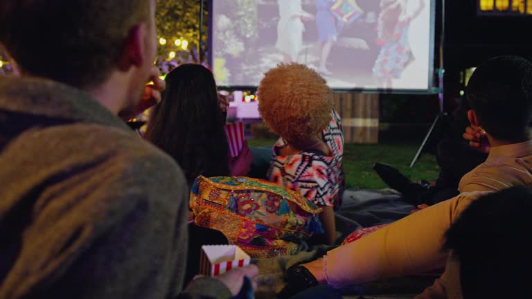 Friends watching movie on projection screen in backyard