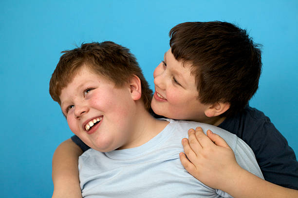 istock siblings: cute overweight boys hugs in front of blue wall 109867980