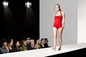 Model wearing red swimsuit on catwalk at fashion show