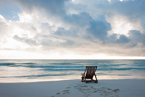 Deck chair on sandy beach at water's edge  tranquil scene stock pictures, royalty-free photos & images