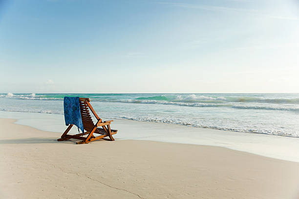 Deck chair on sandy beach at water's edge  deck chair stock pictures, royalty-free photos & images