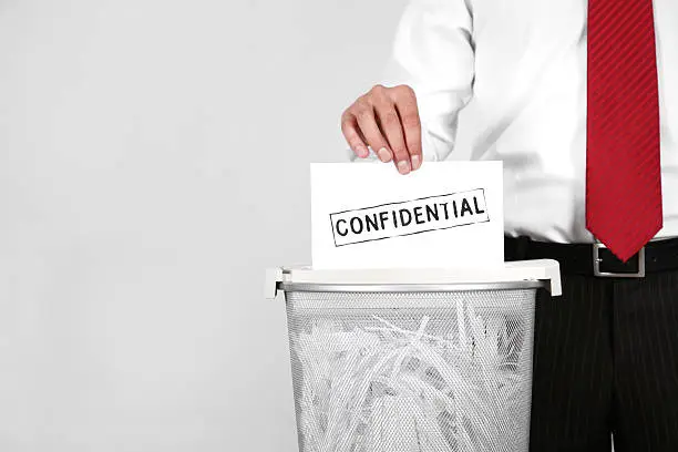 man at office shredding a confidential document.