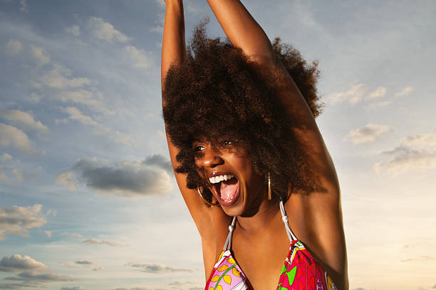 istock Joyful woman with hands raised shouting in joy against sky 110826667