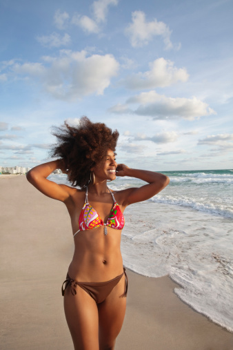 Happy sensuous African American woman standing on the beach