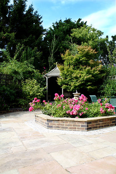 Pretty Patio Wide angle view of a pretty English patio with rose flower bed in the middle, gazebo just visible in the background english rose stock pictures, royalty-free photos & images