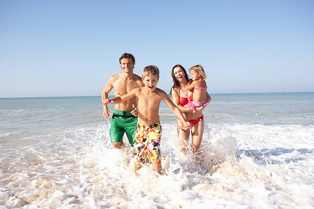 Young family playing on beach  one piece swimsuit photos stock pictures, royalty-free photos & images
